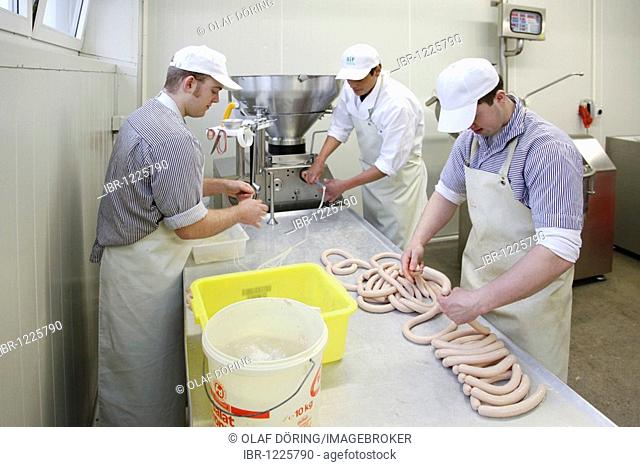 Butcher apprentice creating sausages, boiled sausage at the vacuum filling machine, master school, apprenticeship training position at Frischezentrum e