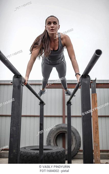Low angle view of female athlete doing push-ups on parallel bars during crossfit training