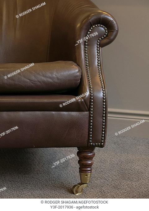 The armrest of an old leather chair with brass studs