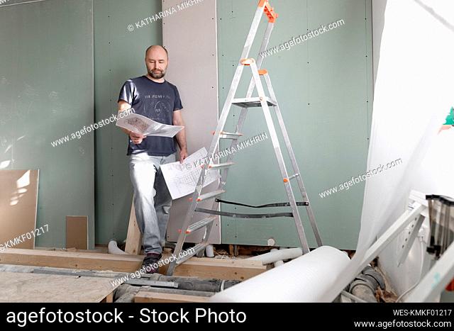 Man on construction site at home studying plan