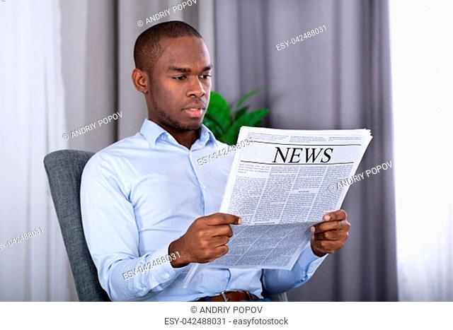 Portrait Of A Young African Man Reading Newspaper