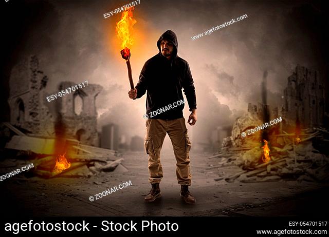 Destroyed place after a catastrophe with man and burning flambeau concept