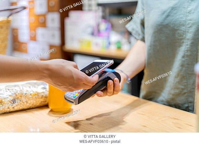 Customer paying cashless with smartphone in a shop
