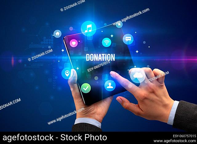 Businessman holding a foldable smartphone with DONATION inscription, social media concept