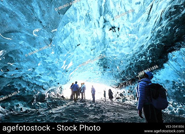Tourists exploring a ice cave in Breidamerkurjökull glacier, which is an outlet glacier of the larger glacier of Vatnajökull (region of Austurland, Iceland)