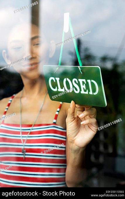 Attractive Asian business woman turning the closed sign of her shop