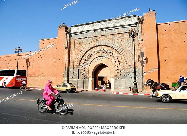 Veiled woman driving a moped past the Bab Agnaou gate in Marrakech, Morocco, Africa