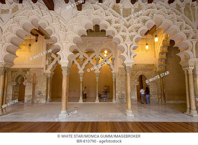 Tourists beneath the ornate stone carved arched passageway of the Santa Isabel Patio, Palacio de Aljaferia palace, Moorish architecture, Zaragoza, Saragossa