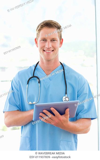 Happy doctor writing on clipboard beside windows