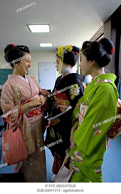 Gion area. Three Maiko or apprentice geisha wearing kimonos, talking and laughing after finishing their classes at Mia Garatso school for Geisha and Maiko