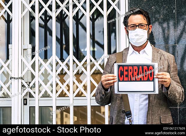 Portrait of man wear medical mask for coronavirus economy crisis with closed business and cerrado spanish panel - concept of unemployed people after covid-19...