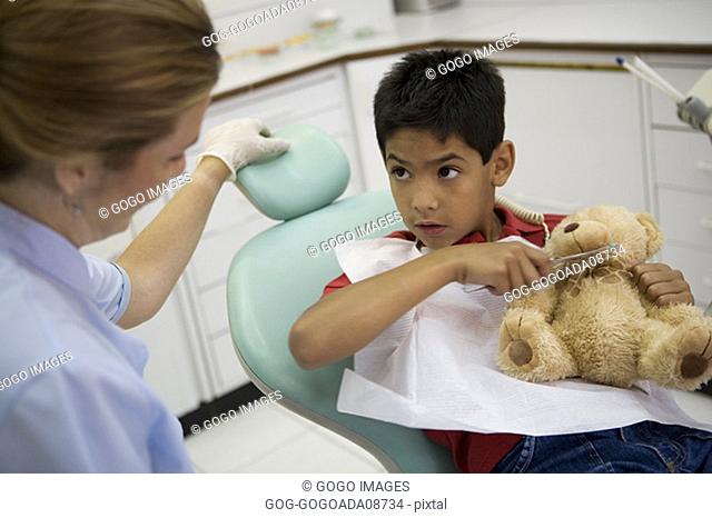 Young dental patient demonstrating tooth-brushing teddy bear