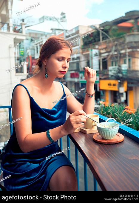 Beautiful woman enjoying tea and dessert on cafe terrace in Dalat, Vietnam