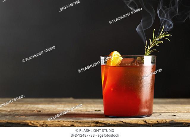 Red fruit cocktail with burnt rosemary and citrus