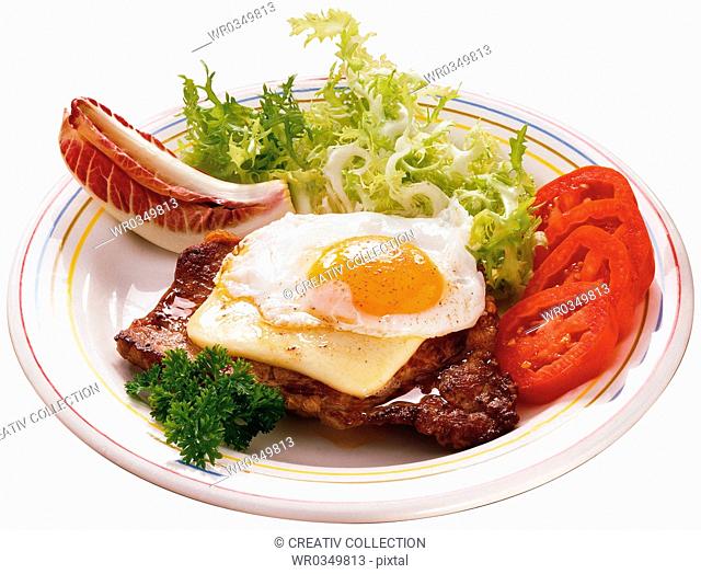 fried steak and egg on a salad plate