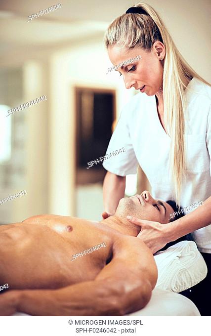 Sports massage. Physical therapist massaging man's neck