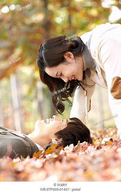 Young Couple Lying On Leaves In Autumn