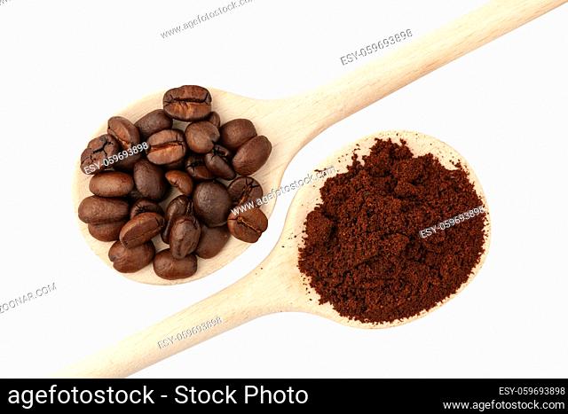 Two diagonally arranged wooden wooden spoons, one each with freshly roasted and ground coffee beans, isolated on white