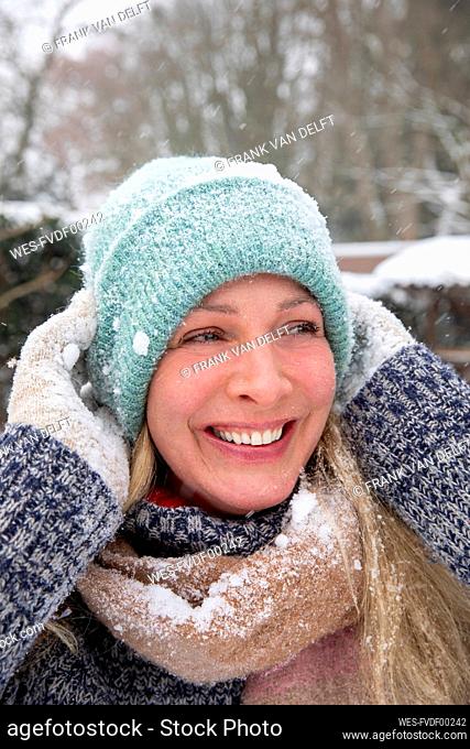 Mature woman wearing knit hat laughing while looking away