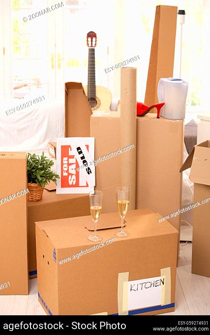 Pile of boxes in new house, champagne to celebrate moving to new home