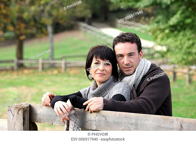 Couple stood by wooden fence