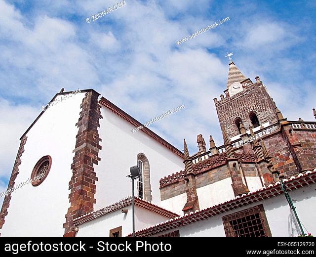 the historic Cathedral of Our Lady of the Assumption in Funchal Madeira a historic gothic style 15th century building in sunlight with a blue cloudy sky
