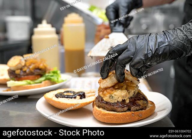 Chef cooking burger, close-up, making sandwich, fast food concept, recipe of preparing homemade hamburger with vegetables. High quality photography