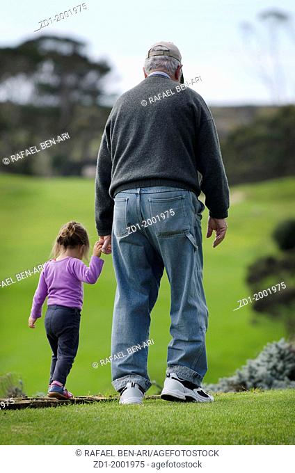 Grandfather walks and hold hands of his grand daughter