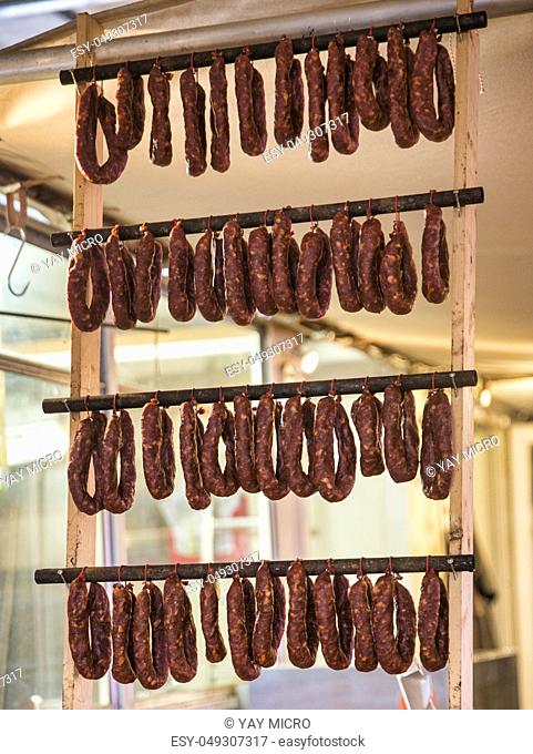 rows of sausages hanging and drying in the shop , ready for sale