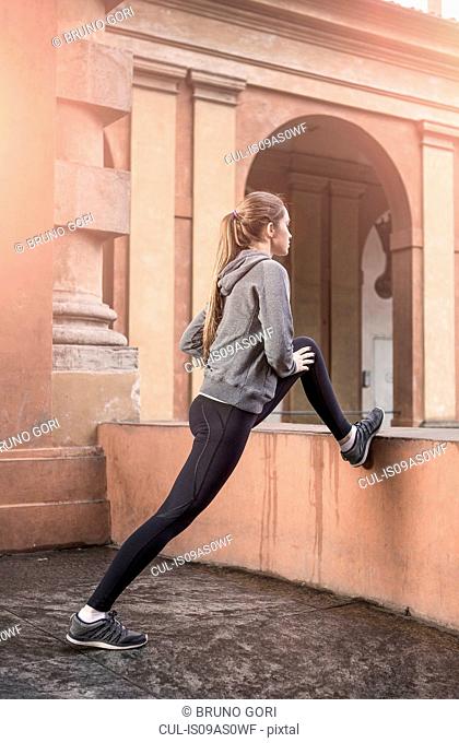 Young woman wearing sports clothes stretching legs