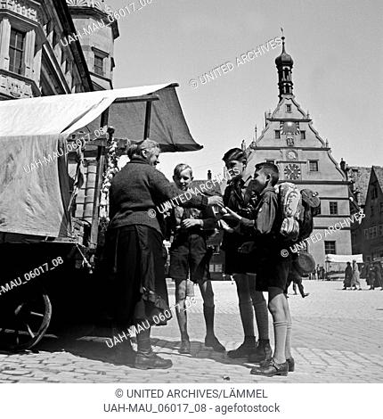 Eine Marktfrau schenkt drei Hitlerjungen Obst von ihrem Stand auf dem Markt in Rothenburg ob der Tauber, Deutschland 1930er Jahre