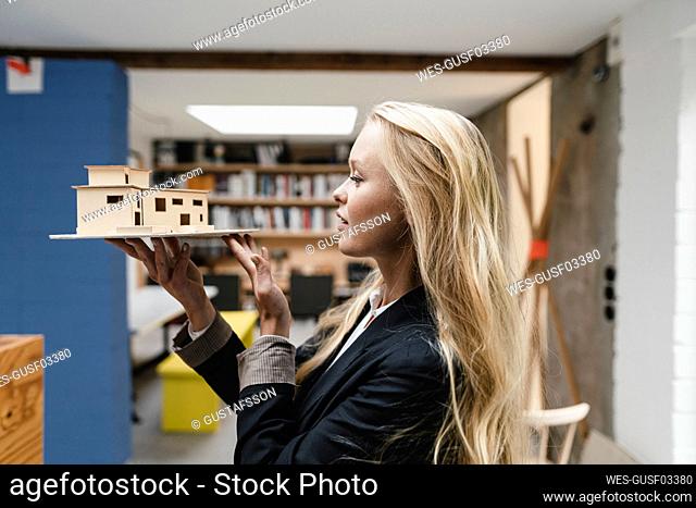 Young businesswoman in loft office holding architectural model