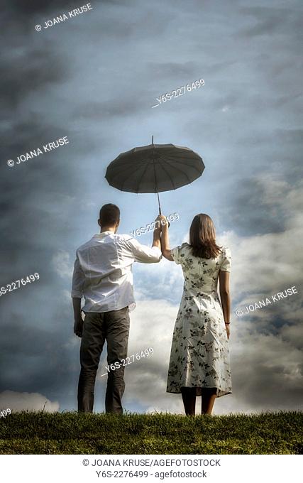 a couple on a meadow with an umbrella
