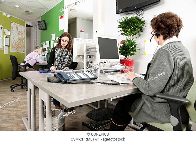 Several women working at the helpdesk of a hospital, answering questions from patients over the phone