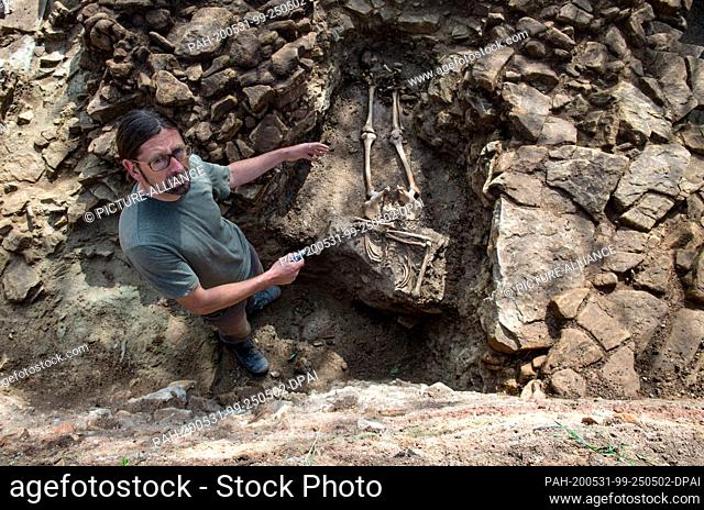 28 May 2020, Saxony-Anhalt, Zeitz: Holger Rode, archaeologist, stands next to a burial in an excavation in the area of the former Posa monastery near Zeitz