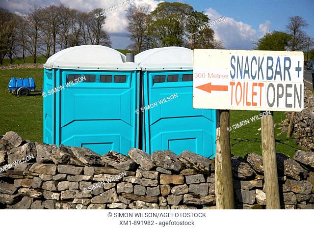 Rural cafe sign and portable toilets in a field