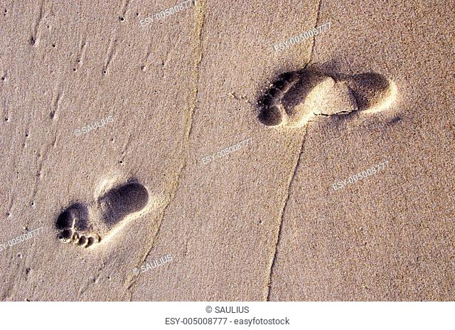 Bare human footprints in sea sand. Rest near sea