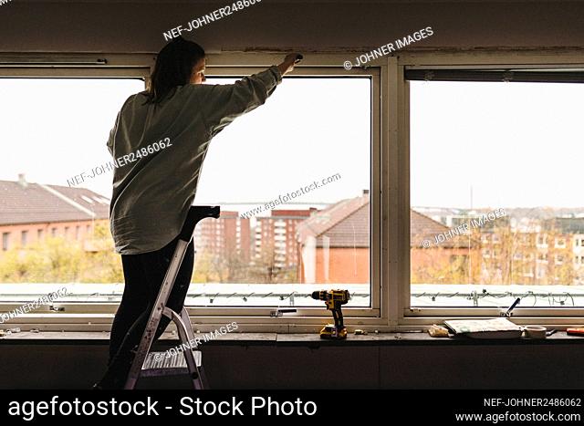 Woman sanding window frame