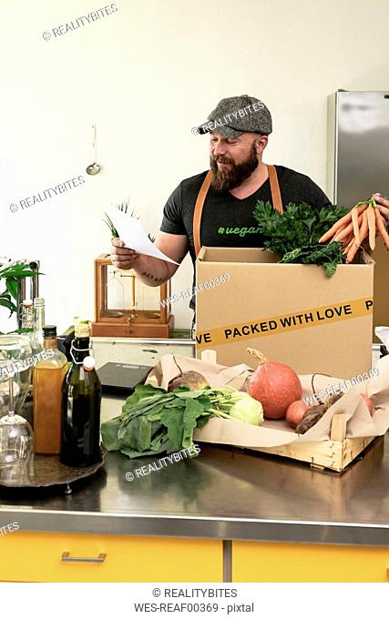 Mature man with delivery service packing organic vegetables in cardboard