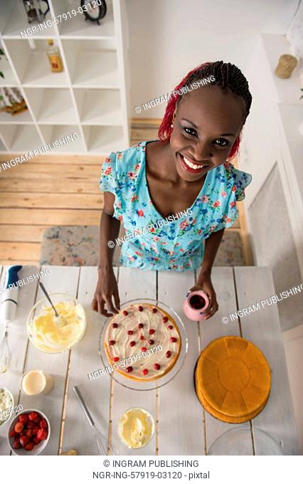 Beautiful young african woman cooking cake at kitchen. Top view