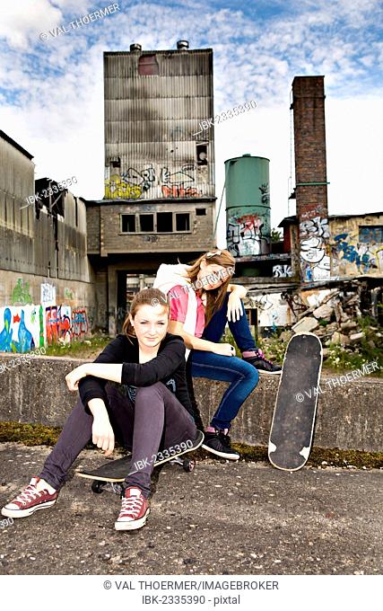 Two young teenage girls with skateboards in an urban area