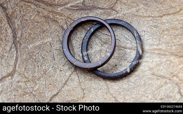 Horizontal photo of His and Hers handmade coconut rings with coconut interior background. Artisan wedding ring bands. Love and union concept