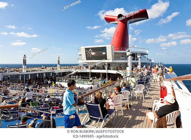 Cruise passengers watching big screen tv outside on deck of Carnival's Triumph cruise ship in the Gulf of Mexico
