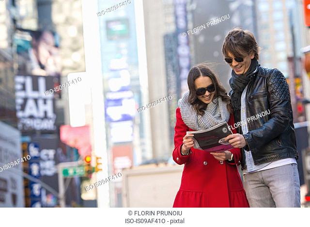 Young tourist couple looking at newspaper, New York City, USA