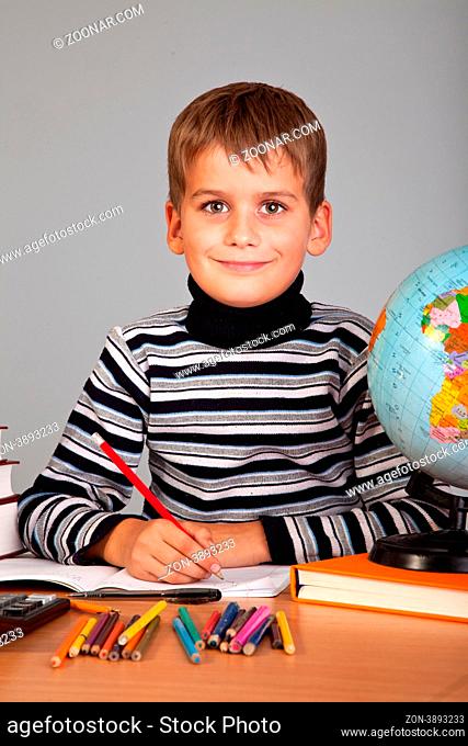 Cute schoolboy is writting isolated on a white background