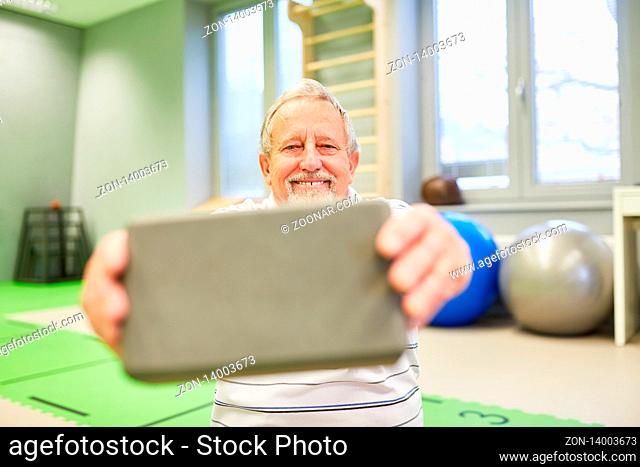 Lächelnder Senior Mann mit einem Yogablock für Rehasport im Fitnesscenter