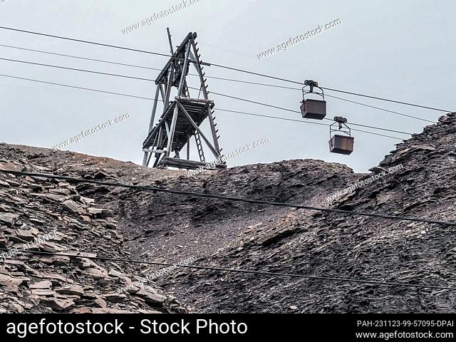 22 August 2023, Norway, Longyearbyen: Empty coal crates hang from a cable car above a road on the mountainside near a former mine