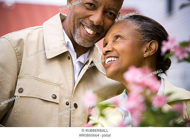 Close-up of a senior man and a senior woman smiling behind flowers