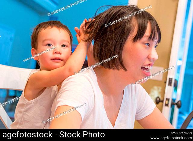 Happy Mixed Race Chinese and Caucasian Boy Having Fun with Chinese Mother Inside House