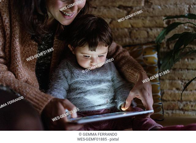 Mother and daughter using digital tablet at home